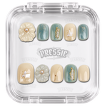 Faux ongles beiges et verts à fleurs en relief et détails dorés, présentés dans leur boîte Pressie Nails — Donghun. @product